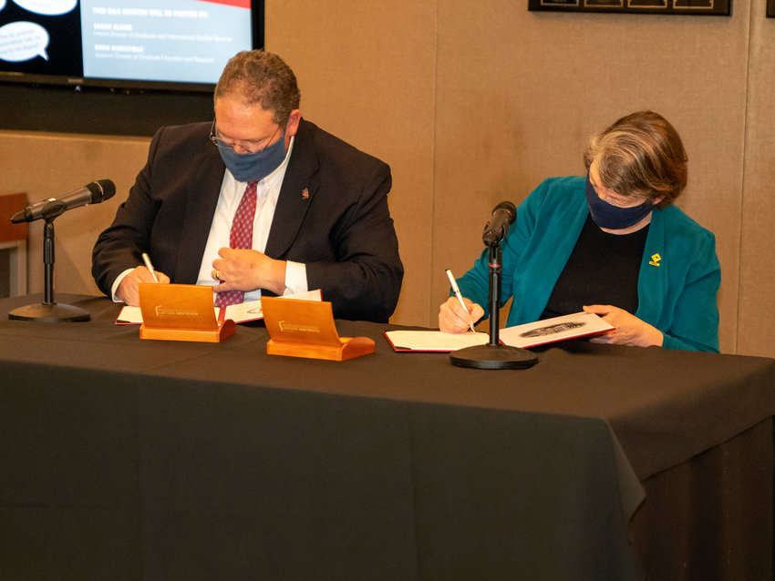 Phil Bridgmon, left, University of Central Missouri provost and vice president for Academic Affairs, and Barbara Glesner Fines, J.D., dean, and Rubey M. Hulen Professor of Law at the University of Missouri-Kansas City, sign an agreement that creates a new pathway for UCM students to pursue a law degree faster and at less cost than a traditional educational pathway.