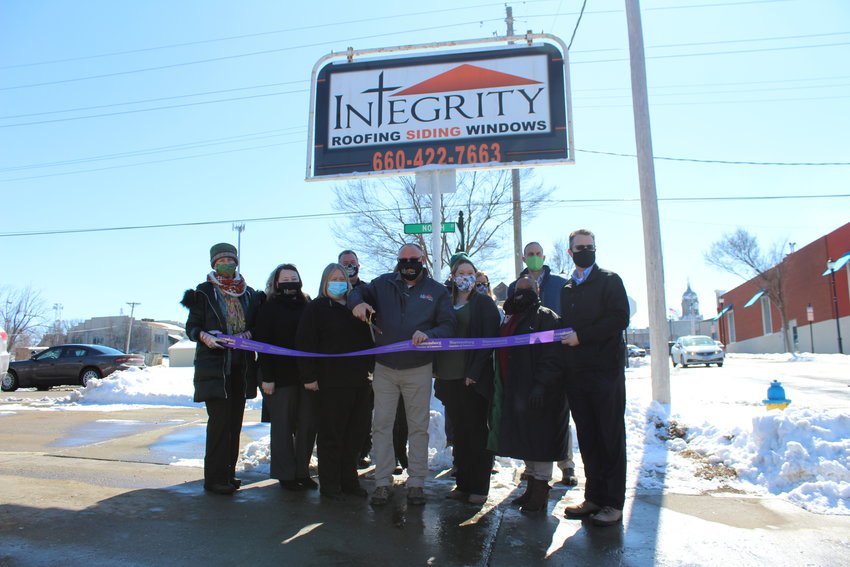 Integrity Roofing Roofing, Siding &amp; Windows Sales Consultant David Schnorenberg prepares to cut the ceremonial ribbon alongside Integrity staff members and Warrensburg Chamber of Commerce members.