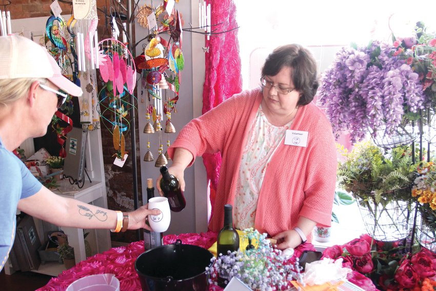 Volunteer Barbara Carroll serves wine from Wildlife Ridge Winery as part of Come, Sip, Shop on Saturday, May 14, in Awesome Blossoms.