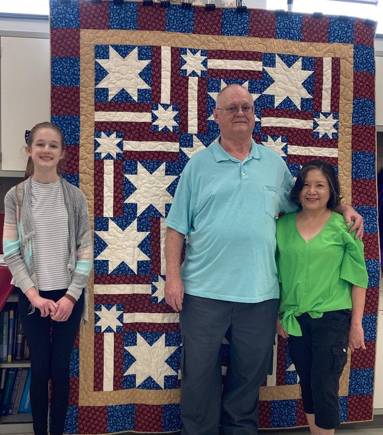 Richard Waltemath, center, stands with his wife, Charity, as he is awarded a Quilt of Valor by Lorelai Kuecker, 13, left, May 13 at the Whiteman Air Force Base Veterinary Clinic.