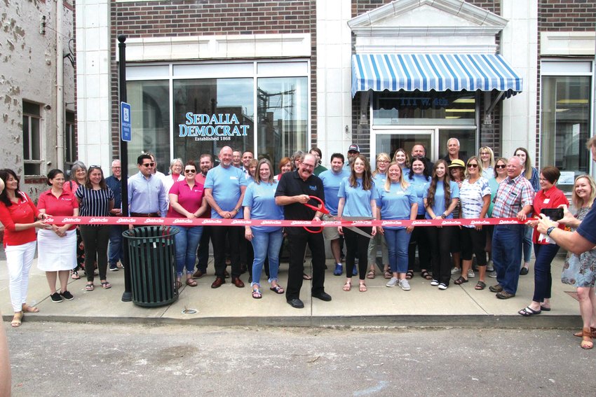 Surrounded by community members, elected officials and employees, Sedalia Democrat Publisher Jim Perry cuts the ribbon celebrating the Sedalia Democrat&rsquo;s new location at 111 W. Fourth St. during an open house hosted Friday, June 10. The new building, formerly the Sedalia Water Department, is across the street from one of the Democrat&rsquo;s past locations at 108-110 W. Fourth St. It began operations at the new building May 2. The Democrat owns the Star-Journal.