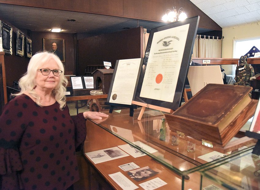 Susan Rouchka, a member of the Pettis County Historical Society, stands with a Bible and other items belonging to John Dalton Russell, the publisher of the Sedalia Democrat from 1871 to 1873. The Bible and documents are on display at the Pettis County Museum.