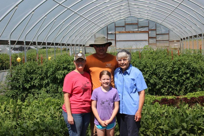Heather, Buck, Jeanne, and Reese Counts pose for a picture in front of one of their greenhouses full of fresh blackberries. Fresh berries are one of the best sellers for Buckeye Acres Produce during the summer months.