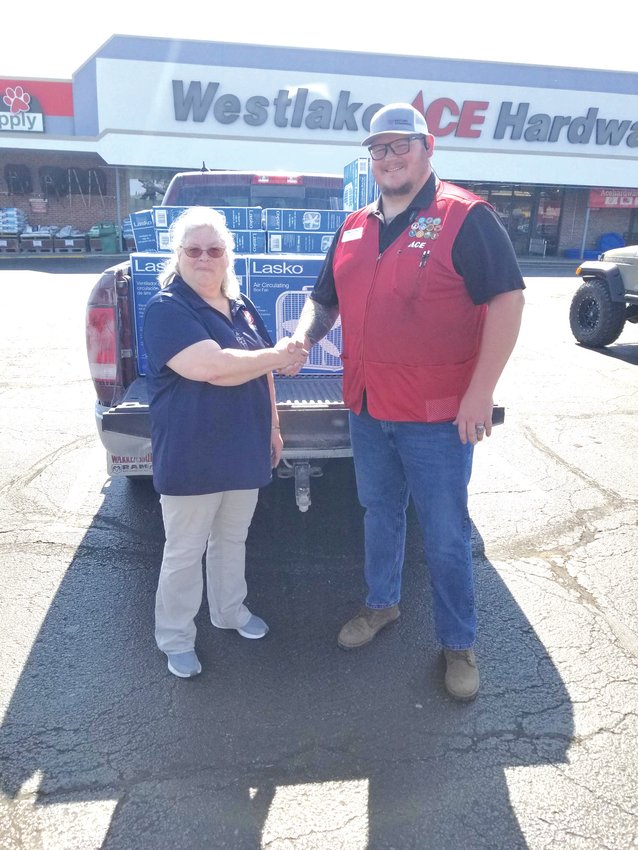 Karen Eagleson, service coordinator for The Salvation Army of Johnson County, accepting fans from Jeff Brown, general manager of Westlake Hardware in Warrensburg.