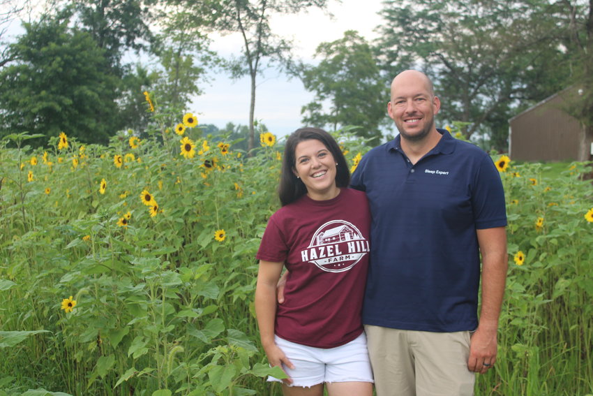 Stacey and Jon Howerton stand with their newly grown sunflowers. The Howertons are the owners of Hazel Hill Farm in Centerview.