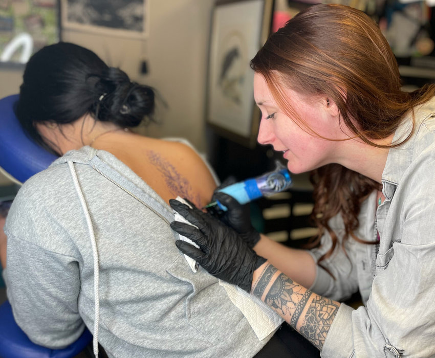 Jessica Neel, owner of Body, Soul, Art LLC Tattoo Studio, 401 Angus Lane in Knob Noster, has to expand her business after a successful first year. Thursday, she inks a floral spine tattoo to loyal customer Erin Bonner, of Windsor.   Photo by Chris Howell | Democrat