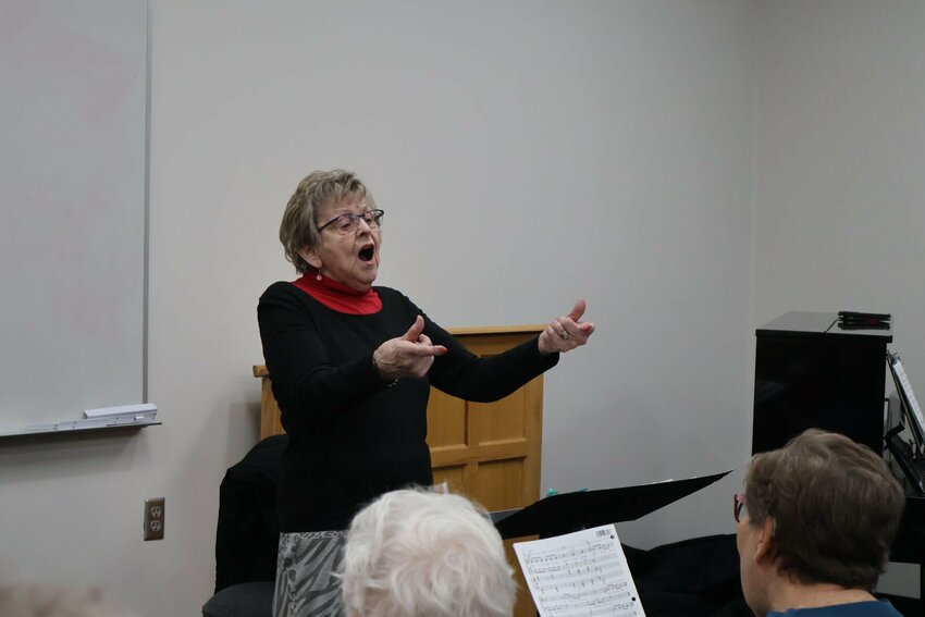 Director Cathi Truesdale, with arms extended, directs the Warrensburg Community Chorus in rehearsals on Tuesday, March 21.&nbsp;
