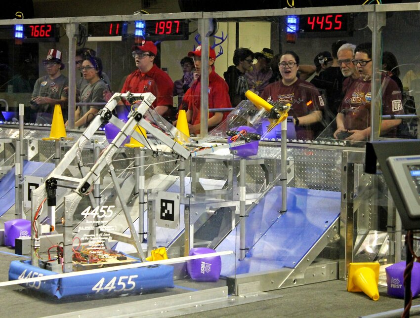 Members of the Warrensburg High School robotics team, from left, Mariah Penniman, coach Brian Holmgren and Scott Swainston watch as their robot, 4455, completes a game task during a qualifying match Friday afternoon.&nbsp;