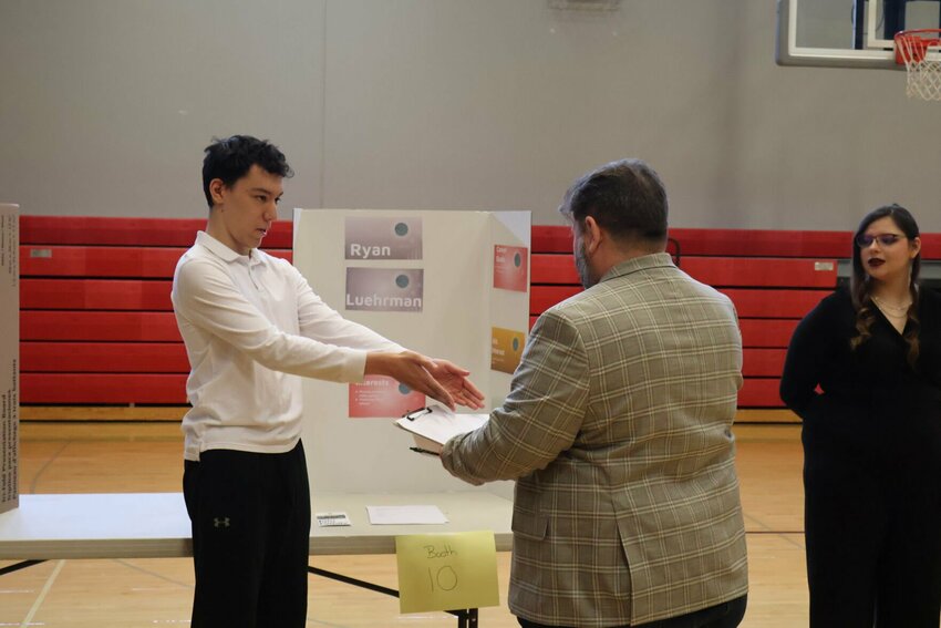 Ryan Luehrman presents his resume to Bryan Jacobs during the Reverse Career Fair on Friday, March 24 at Warrensburg High School.