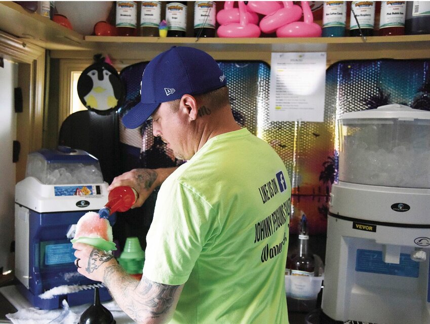 On Wednesday, April 19, Johnny Tevis pours a combination of pink bubblegum and blue cotton candy flavorings over shaved ice at Johnny Penguins in Warrensburg. Tevis co-owns the business with his wife, Jamie. This is the second year for the shop.   Photo by Faith Bemiss | Sedalia Democrat