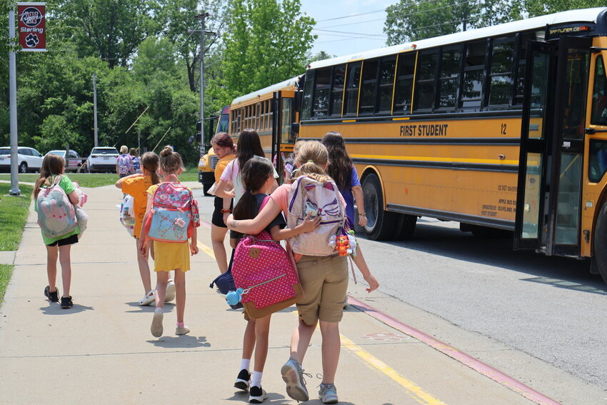 Sterling Elementary students walk with arms intertwined as they head for the bus just before summer break.&nbsp;