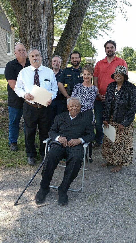 The Reve. W.T. Morris, seated, his wife Dianna Morris and members of the community pose for a photo before the unveiling of the new street sign in Knob Noster last month. The Board of Aldermen approved renaming East Allen Street as W.T. Morris Avenue in honor of Morris.&nbsp;