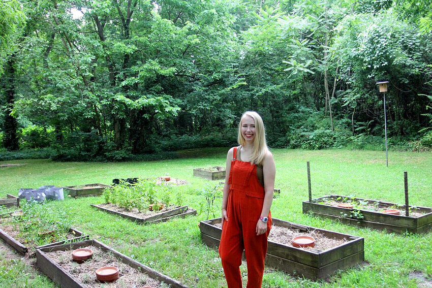 Apothecary's Garden business owner Kymberly Friel stands in front of her raised garden beds filled with plants, including rosemary, basil, thyme, oregano, and more.&nbsp;