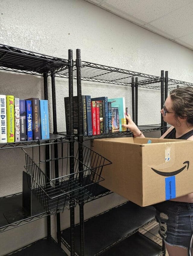 Rebekah Mauschbaugh, co-owner of Lamplight Bookstore, stocks the new business' shelves with used books in early July ahead of the grand opening later this month. The new bookstore is located in the back of Meyer's Market in downtown Warrensburg.   &nbsp;