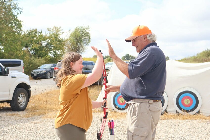 A volunteer high-fives a girl after she shot a bullseye at the WILS Outdoors Without Limits event on Wednesday, Sept. 20 at Hazel Hill Lake.