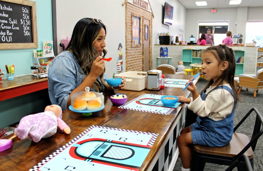 Melanie Morales and her daughter, 2-year-old Camila Rodriguez, enjoy some &quot;lunch&quot; at Ema's Diner while visiting My Little Town on opening day Monday, Sept. 25. Morales, of Whiteman Air Force Base, said they are originally from Chicago, where businesses like My Little Town are common, so she was excited to hear about the new offering in Warrensburg. She said they were having a lot of fun, and Rodriguez especially liked all the stuffed animals at the vet's office.