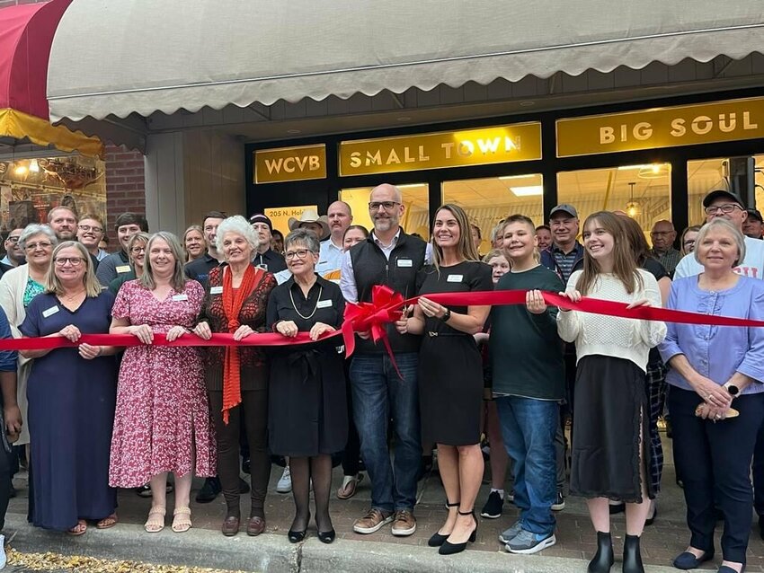 Warrensburg Convention and Visitors Bureau Tourism Director Marcy Barnhart, center, is surrounded by WCVB board members, community supporters and Warrensburg Chamber of Commerce members as she prepares to cut the ribbon for the new Visitors Center on Wednesday, Nov. 8.