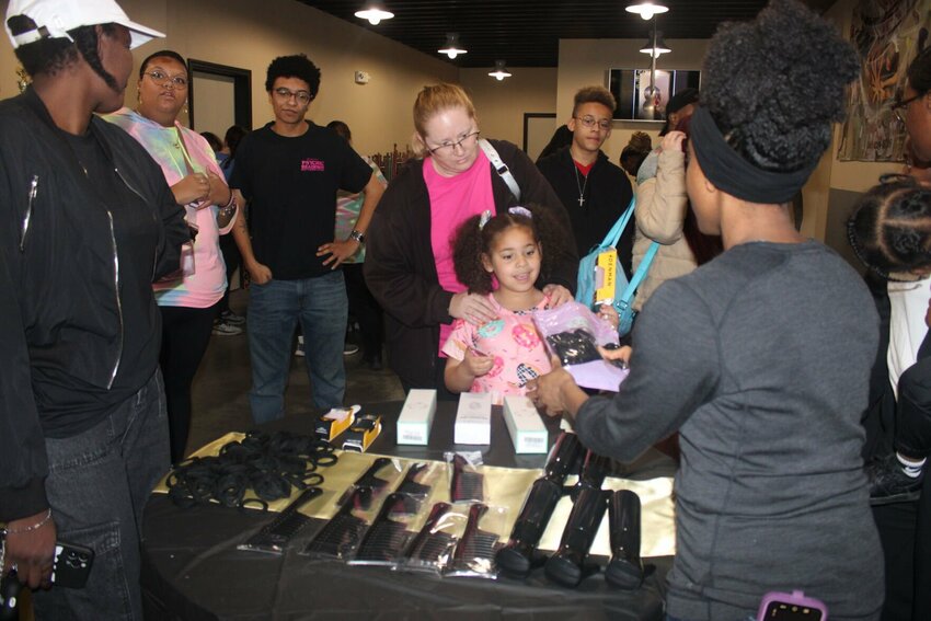 Attendees of the hair seminar gather around for free hair care products, which guest speaker Lt. Col. Simmona Ahn referred to as tools for success. The African American Heritage Association and the Diversity Equity and Inclusion organization from Whiteman Air Force Base hosted the event Wednesday, Feb. 21 at the Youth Excited About Sports Center in Warrensburg.