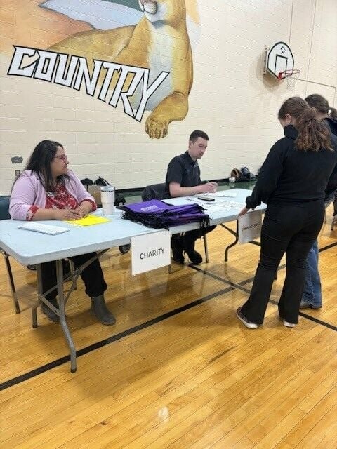 Volunteers Monica Mitcheltree, left, and Max Ridenhour talk with students who stop by the charity table during a Reality Check event hosted by Central Bank on Thursday, April 11 at Crest Ridge High School.