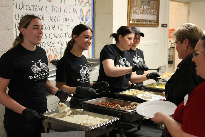 Staff members of Mary Jane's Cafe hand out breakfast items such as eggs, biscuits and bacon to community members during the Warrensburg Chamber of Commerce's seventh annual Community Update Breakfast on Friday, April 26, at Bethlehem Lutheran Church.