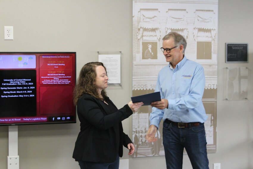 Warrensburg Mayor Bruce Uhler, right, presents Community Development City Planner Kristin Dyer, left, with a designation signifying Warrensburg and Johnson County as a World War II Heritage City on Friday, May 3, at the Warrensburg Visitors Center.
