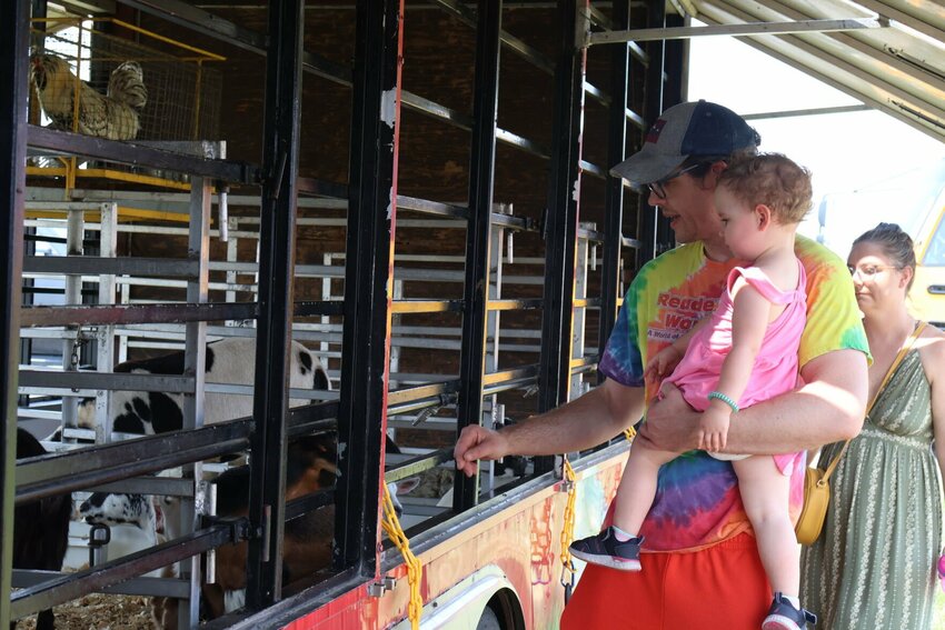 A family visits the farm animals at the Johnson County Fair on July 15, 2023. The trailer had goats, pigs, a cow and more.