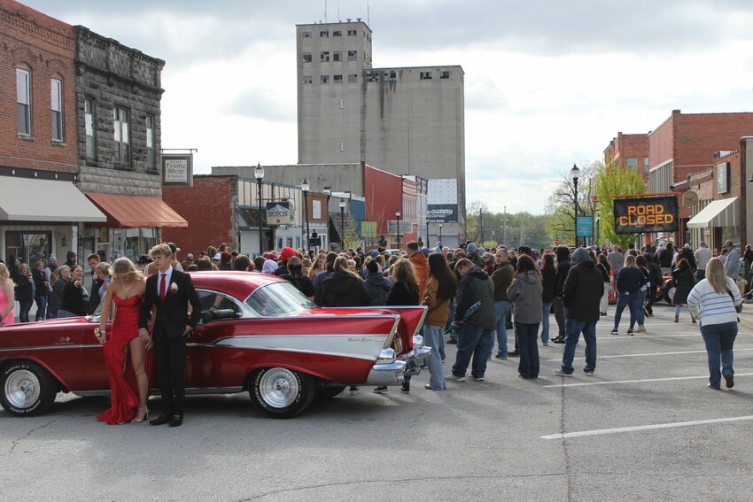 A couple readies themself to pose in front of the 2025 Prom Parade and a classic car on Saturday, April 5, on Pine Street.