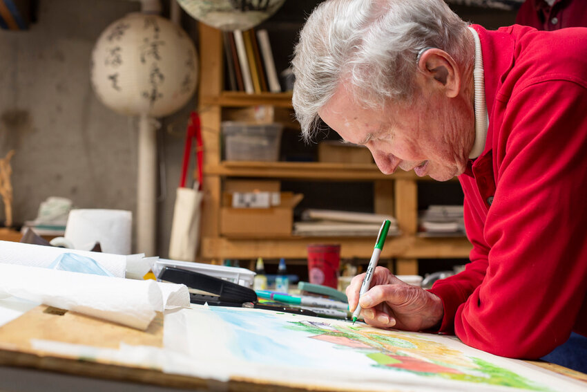 In a photo in 2020, the late Richard Luehrman, Professor Emeritus of Art at the University of Central Missouri, focuses on a watercolor painting of his family home in Lexington, Missouri.