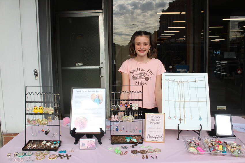Rana Ward poses behind her exhibit selling jewelry like charm bracelets, gold earrings and personalized keychains. The Downtown Warrensburg Art Walk requires that its participants provide their own tables or booths to display their artwork.