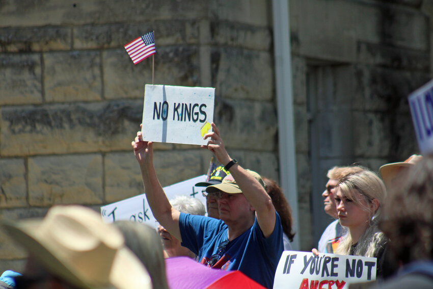 A man holds a sign stating “veterans support and defend the Constitution,” on Saturday, June 14, at the Johnson County Courthouse.