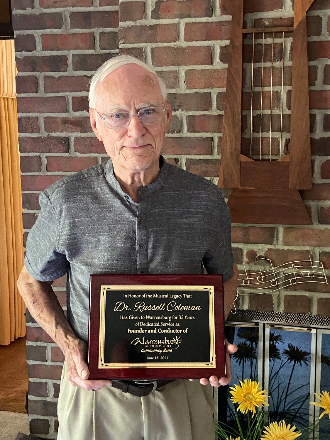 Russell Coleman holds a plaque honoring his 35 years of service as founder and conductor of the Warrensburg Community Band at a celebration June 13. 