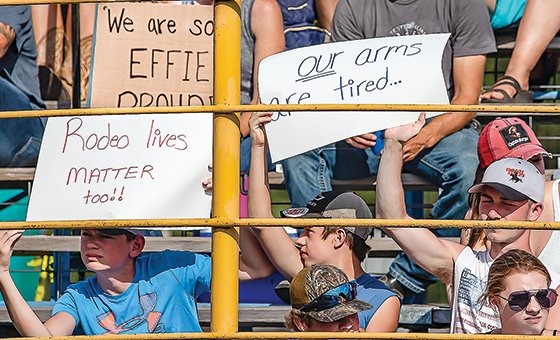 Attendees at the opening session of the North Star Stampede rodeo on Friday wave protest signs.