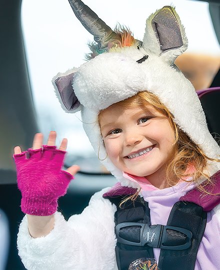 Cora Lantry, dressed up as a unicorn, waves from a car at the Cook Lions Club drive thru candy handout in Cook.
