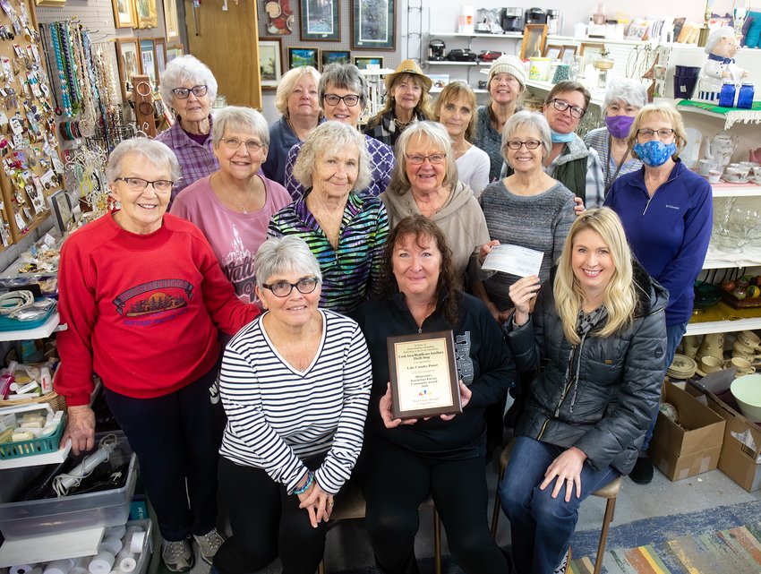 Volunteers of Cook Area Health Care Auxiliary Thrift Shop celebrate receiving a Touchstone Energy Community Award on Monday from Lake Country Power Public Relations Coordinator Tami Zahn, seated right. The service award came with a plaque, held by auxiliary president Kirsten Reichel, seated center, and a $500 check.