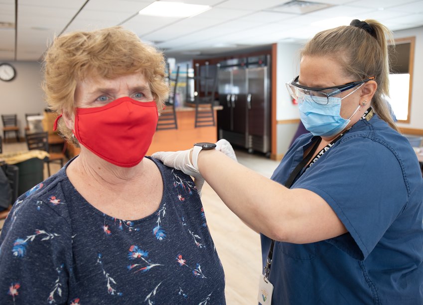 Kathy Plesha, of McKinley, receives her first dose of coronavirus vaccine from nurse Annie Dougherty on Friday at the Cook Community Center.