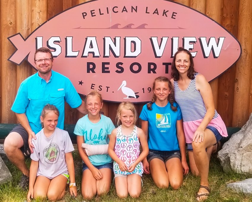 Brett and Alaine Brodeen pose with their daughters Anelise, Corra, Esme and Evelyn in front of their Island View Resort sign at Pelican Lake.
