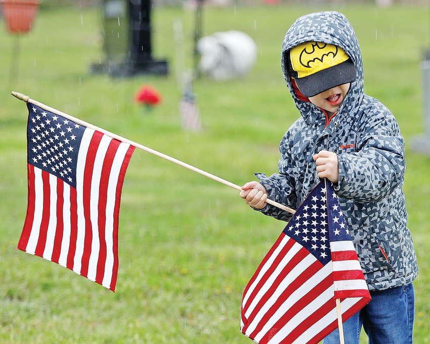 Oliver Weidemann, 5, of Ely, helps place 1,120 American flags at the Ely Cemetery for Memorial Day.