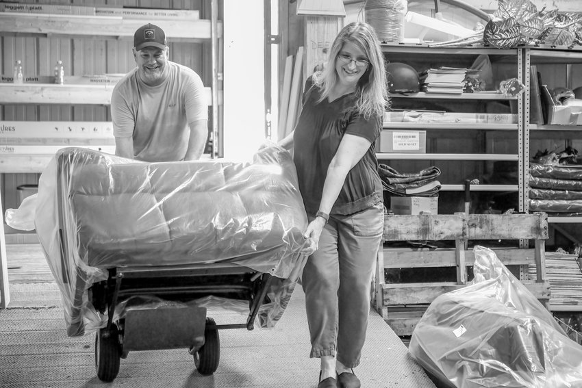 Having avoided most of the unloading because she was working with customers and an inquisitive member of the press, Dawn Bogdan takes a brief break on Monday to help her husband Chris wheel a chair into their newly-named Northern Comfort Company store in Cook.