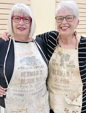 Debbie Olson Shields (left) and her big sister Lynn Olson donned the aprons worn years back by their father and grandfather.