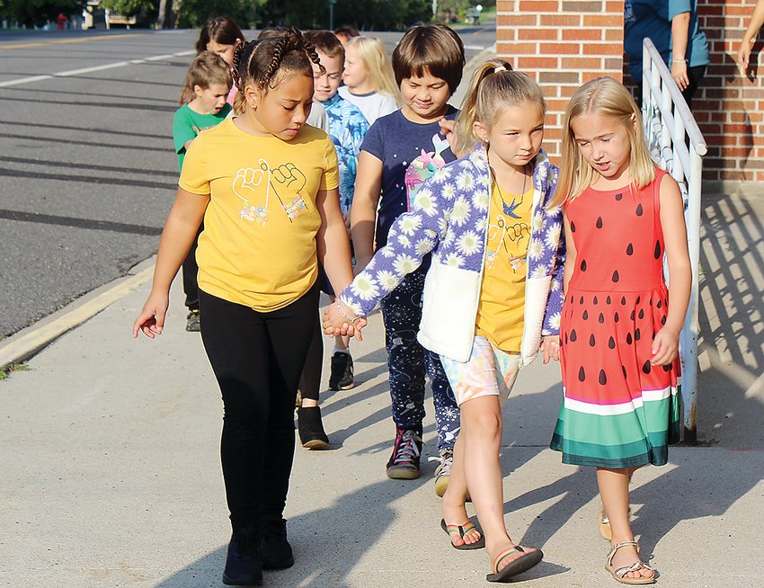 Ivy Russell, Zaija Schroeder, and Cecilia Majerle hold hands on the first day of school.