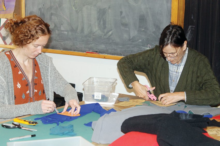 New program coordinator at EFS Alexia Springer traces a pattern while Alison Bell gets down to cutting.
