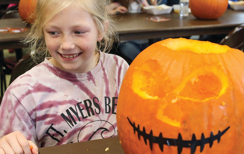 Haley Glatch appears pleased with her pumpkin&rsquo;s scary grin.