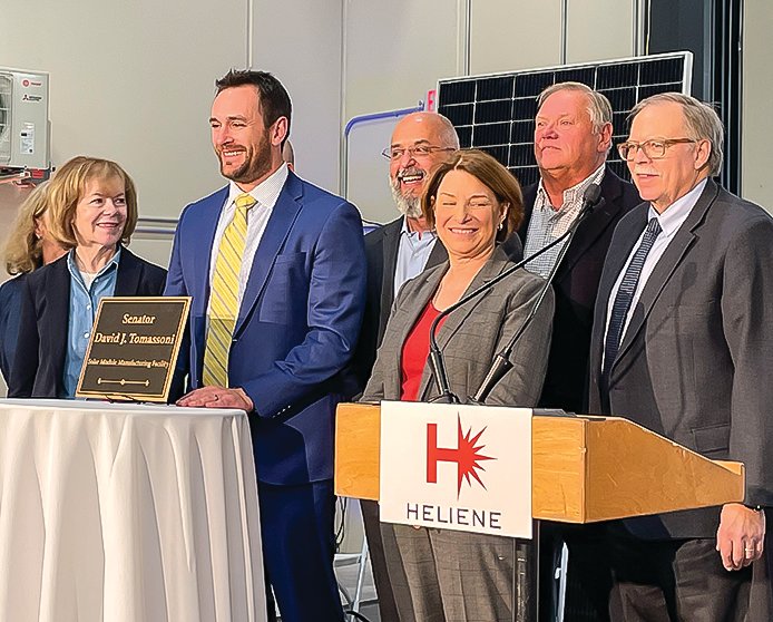 Dante Tomassoni, the son of the late Sen. David Tomassoni is flanked by Sens. Tina Smith and Amy Klobuchar in front of a plaque dedicating the new Heliene expansion to his father. Also pictured are Heliene CEO Martin Pochtaruk, Sen. Tom Bakk, and IRRR Commissioner Mark Phillips.