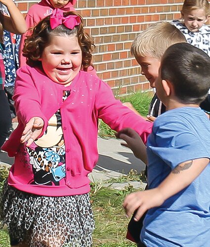 Lucy Pecchia, at a younger age, smiled as she reached for her   brother Dane during recess at school.