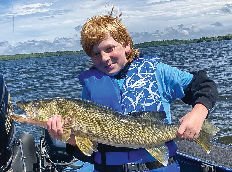 Take A Kid Fishing participant Cass Nelson hoists the 30-inch walleye he caught after   braving the showers that kept most other   participants back on shore.