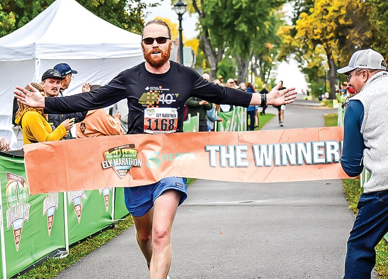 Ely area resident Hudson Kingston outstretches his arms in triumph as he crosses the finish line to take first in last Saturday&rsquo;s Ely Marathon