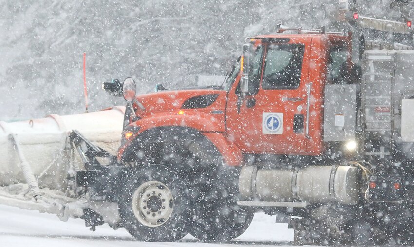 A snow plow heads out in a winter storm.