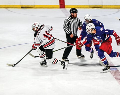 Ely&rsquo;s Deegan Richards takes the puck past two Moose Lake defenders