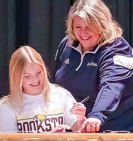 North Woods Head Girls Golf Coach and mom Kandi Olson shows her daughter Tori where to sign a letter of intent to play golf for UM-Crookston this coming fall.