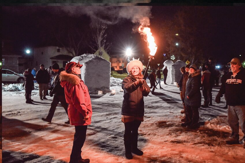 Ely podcaster and Boundary Waters Connect manager, Lacey Squier, was this year&rsquo;s Ely Winter Festival Grand Marshal, shown here with the torch to light the ceremonial fire to officially start the festival on Friday evening.